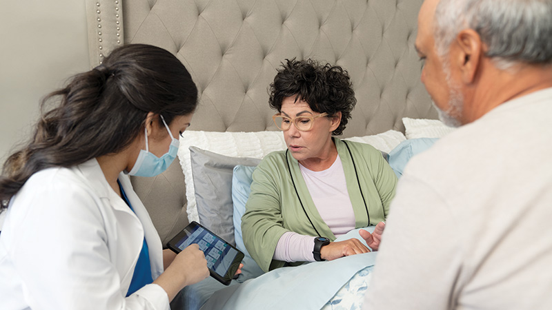 Woman with provider in bed looking at tablet