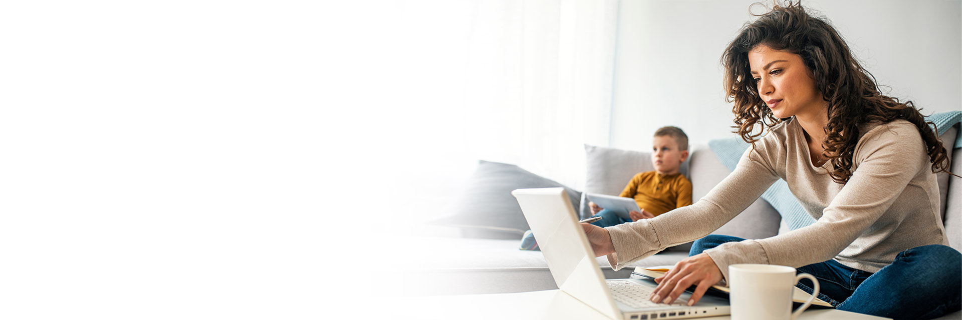 Mom using her laptop while sitting with her son 